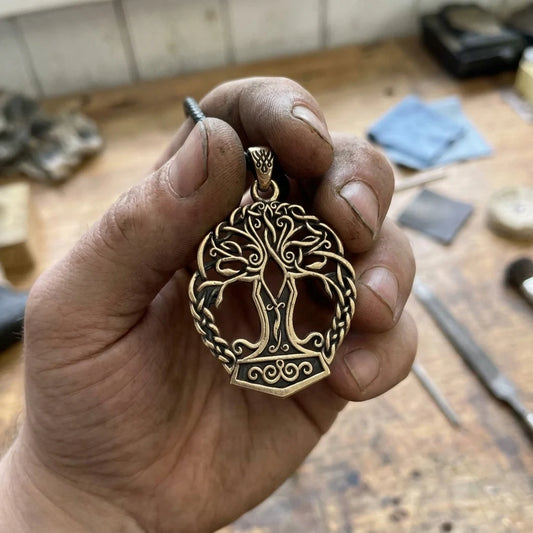 Yggdrasil Mjolnir Thor Hammer Pendant held in the maker's hand in solid brass
